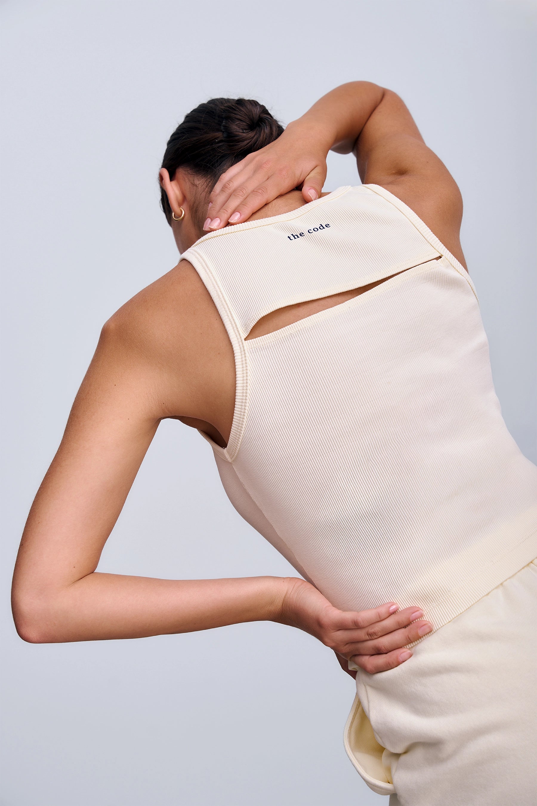 Riva Top Butter Yellow – dopasowany crop top damski z prążkowanej dzianiny w ciepłym żółtym odcieniu z geometrycznym wycięciem na plecach.