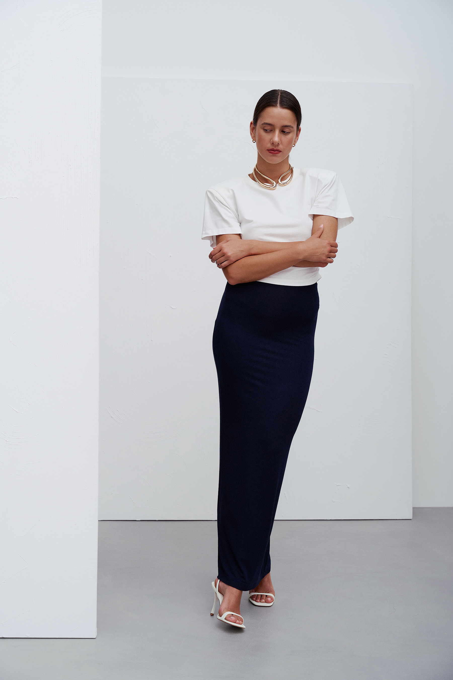 Siena T‑shirt White – minimalistyczna biała koszulka z okrągłym dekoltem i subtelnymi marszczeniami po bokach, które modelują sylwetkę, inspirowana nowoczesną codzienną elegancją.