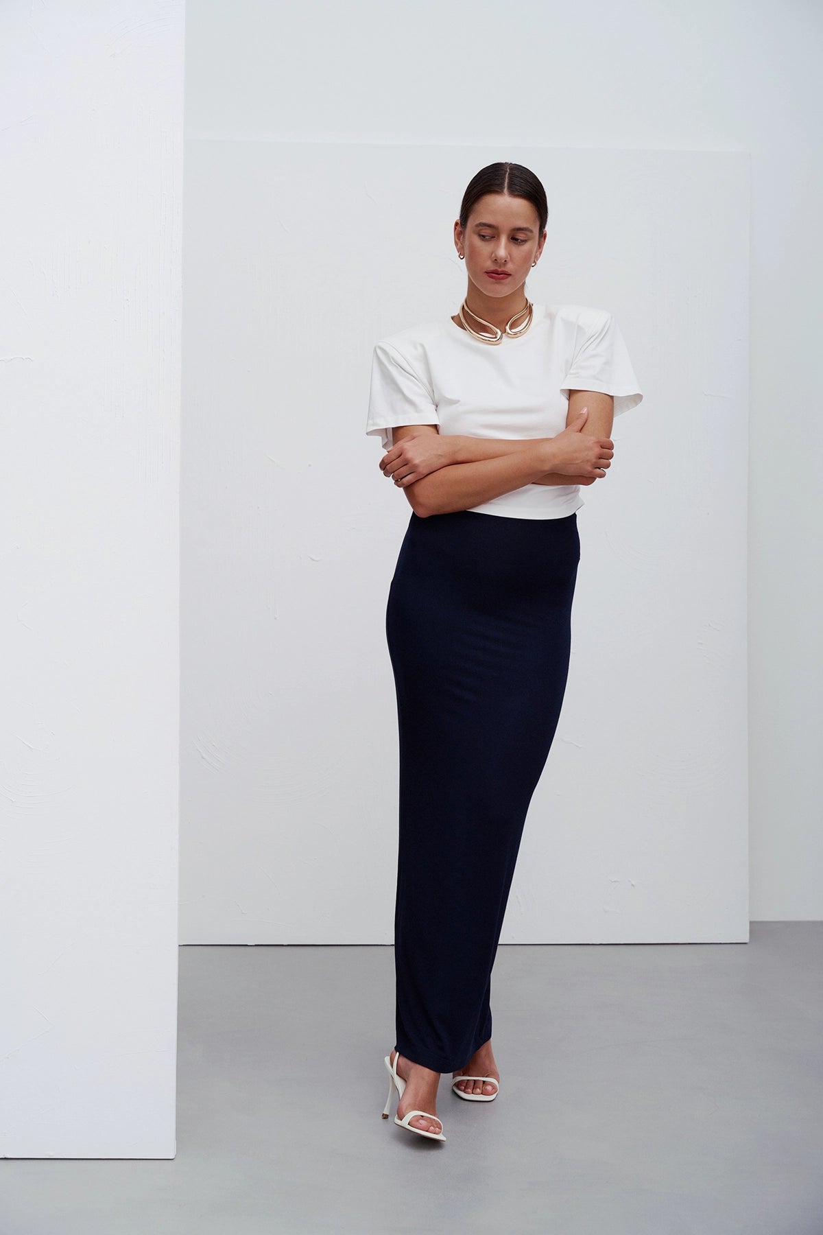 Siena T‑shirt White – minimalistyczna biała koszulka z okrągłym dekoltem i subtelnymi marszczeniami po bokach, które modelują sylwetkę, inspirowana nowoczesną codzienną elegancją.