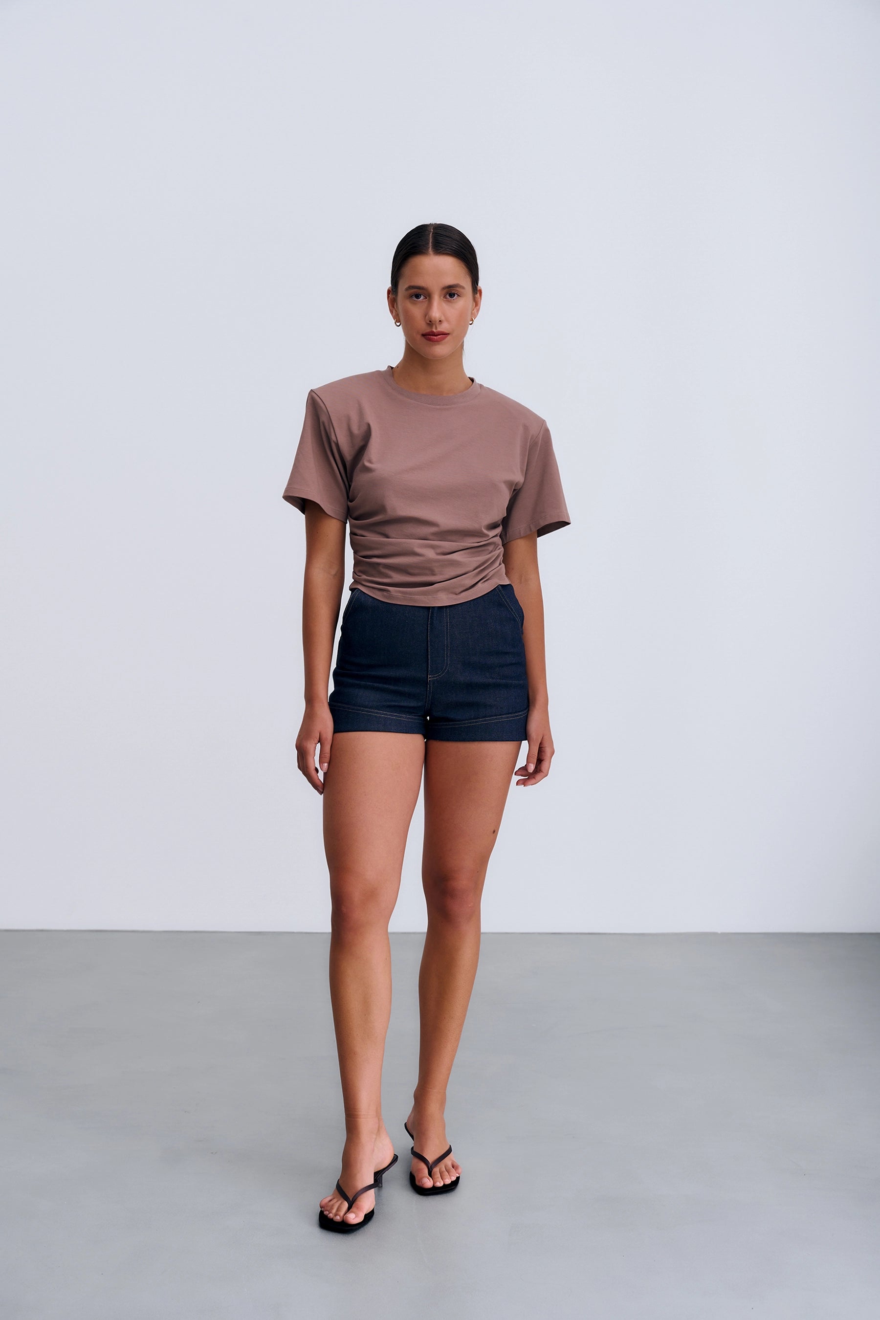 Siena T‑shirt Taupe – damski T‑shirt w kolorze taupe z okrągłym dekoltem, poduszkami na ramionach i subtelnym marszczeniem po bokach.