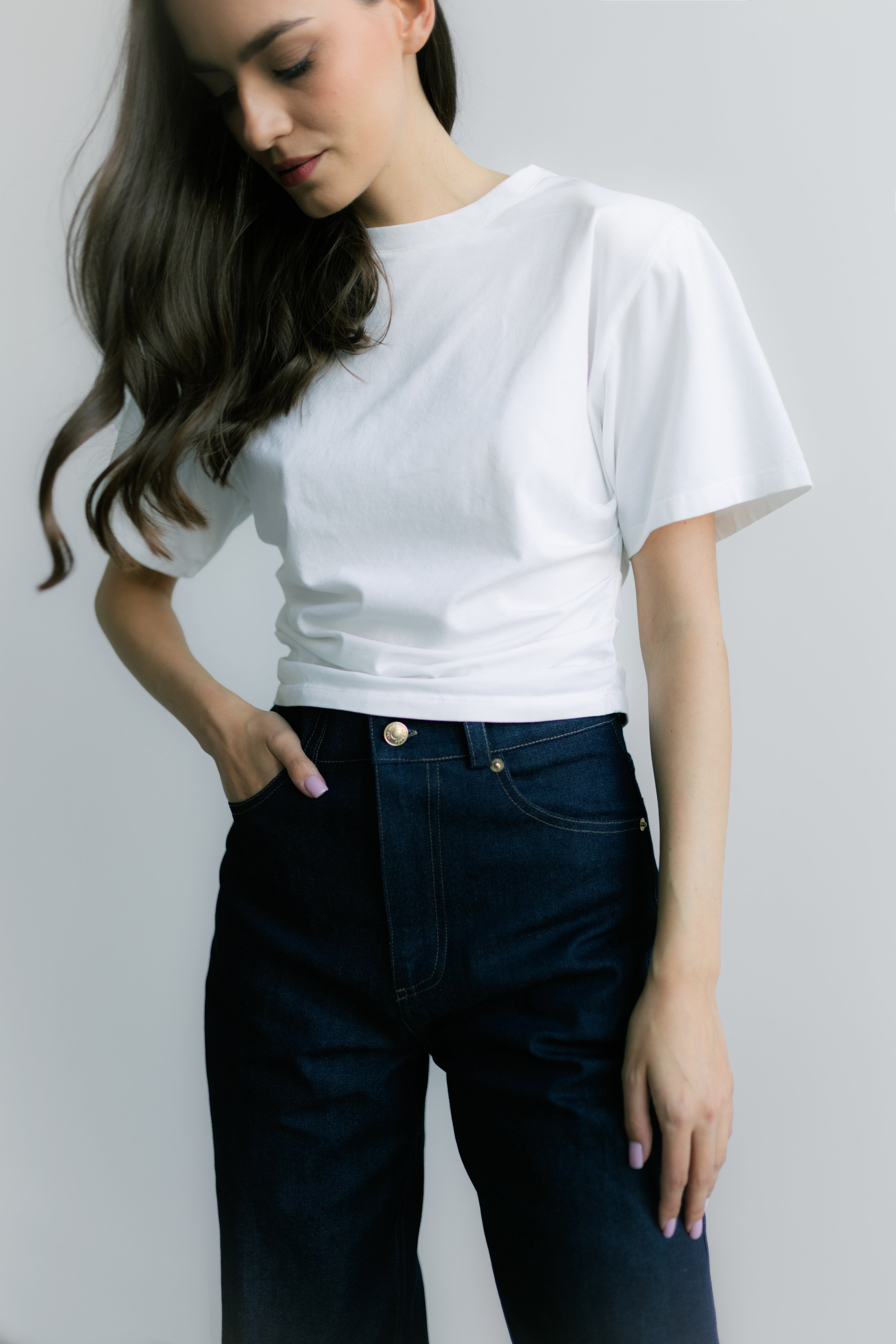 Siena T‑shirt White – biały damski T‑shirt z okrągłym dekoltem, bocznymi marszczeniami modelującymi sylwetkę i poduszkami na ramionach.