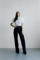 Modelka w Siena T‑shirt White – biały T‑shirt z poduszkami na ramionach, krótki fason i nowoczesny minimalistyczny wygląd.