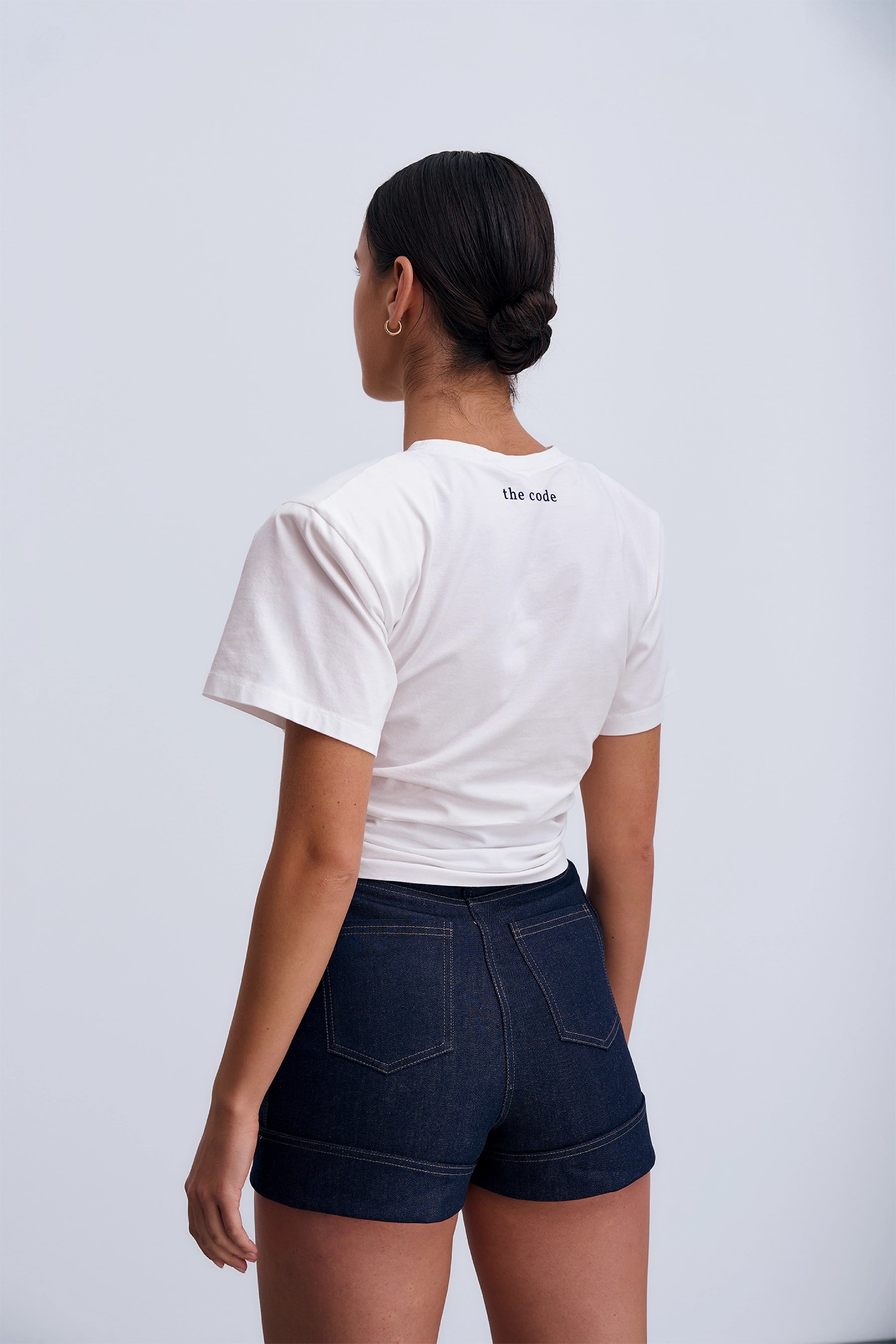 Minimalistyczny Siena T‑shirt White – krótki fason T‑shirtu z bawełnianej dzianiny z elastanem, subtelne logo z tyłu i strukturalne poduszki na ramionach.