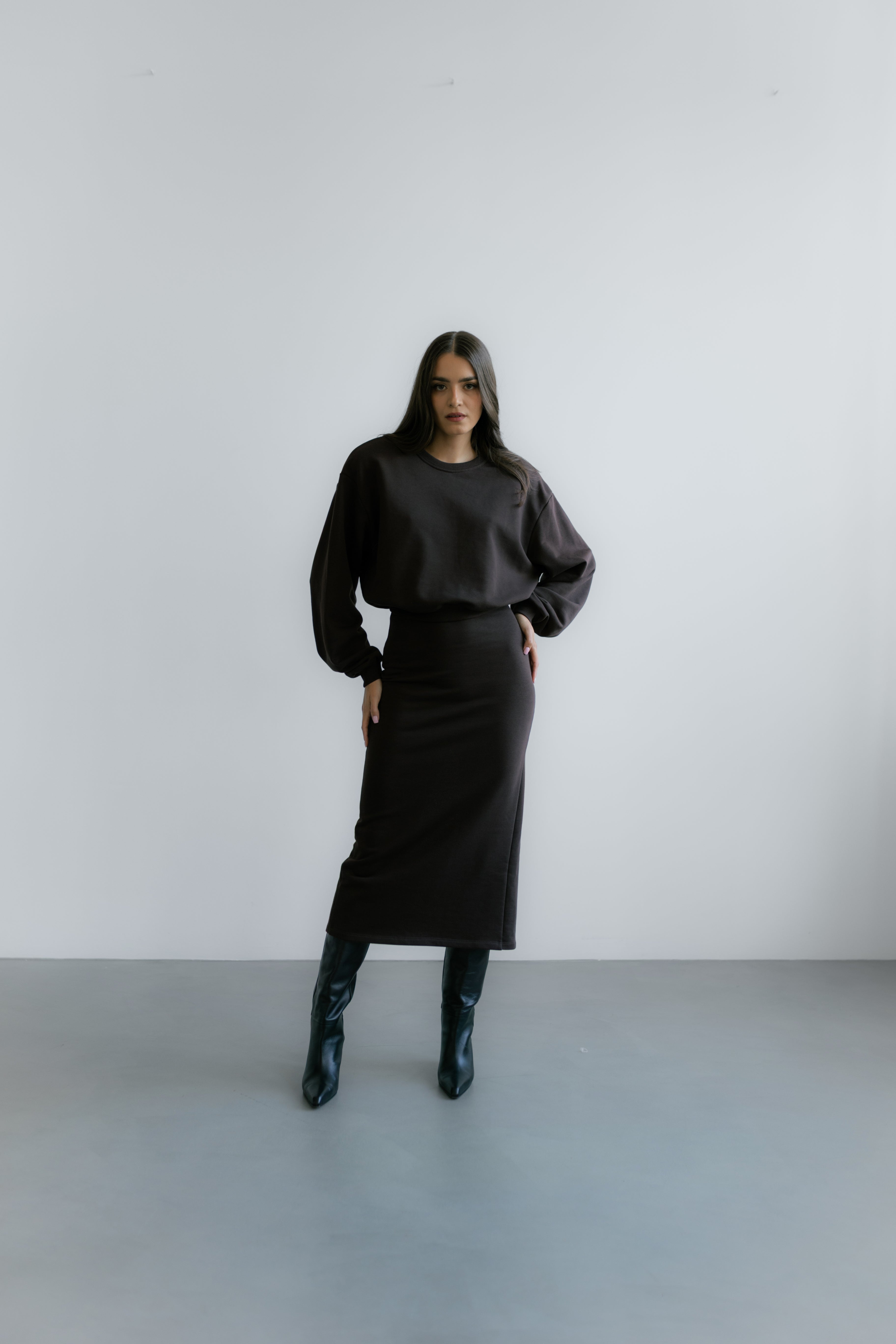 Modelka w Verona Sweatshirt – czekoladowa bluza oversize z poduszkami w ramionach i minimalistycznym, eleganckim wykończeniem.