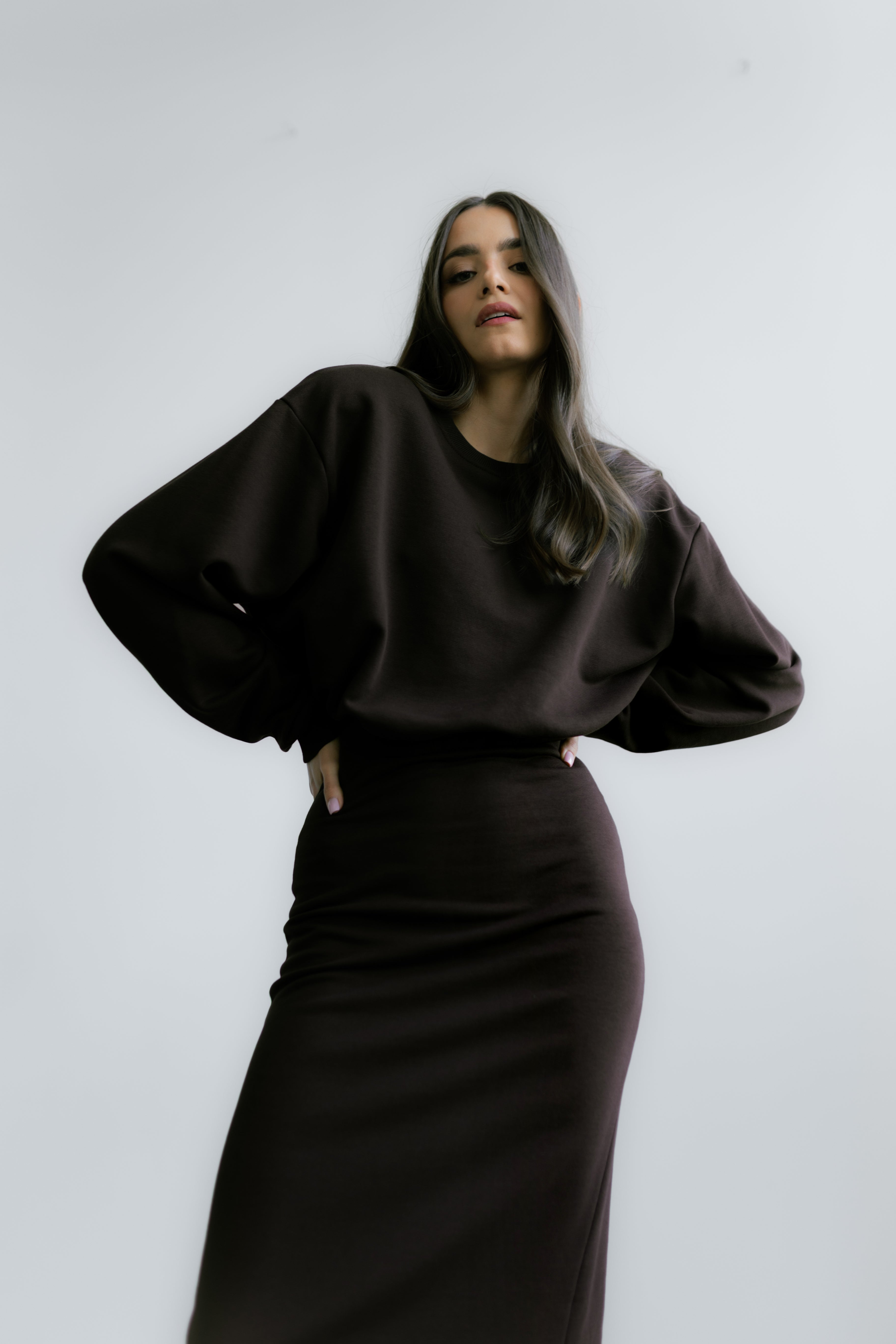 Modelka nosząca czekoladową spódnicę Verona Skirt – dopasowany fason midi idealny do stylizacji z obcasami lub ciężkimi butami.